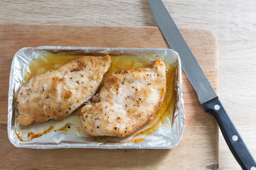 Slices of roasted chicken breast on wooden table, top view