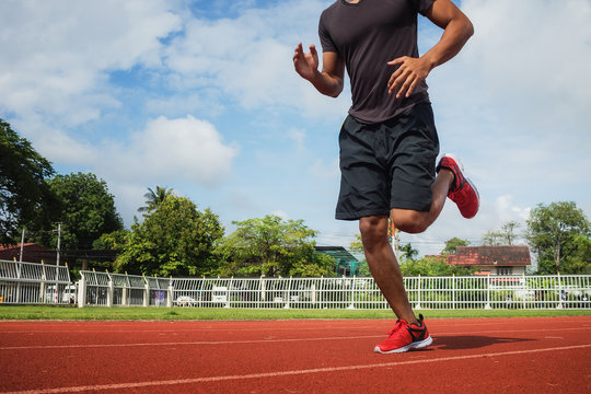 Young man jogging in the morning sun in the stadium.