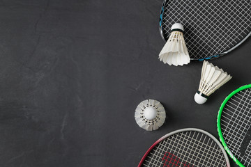 Shuttlecocks and badminton racket on black background. - obrazy, fototapety, plakaty