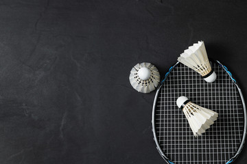 Shuttlecocks and badminton racket on black background