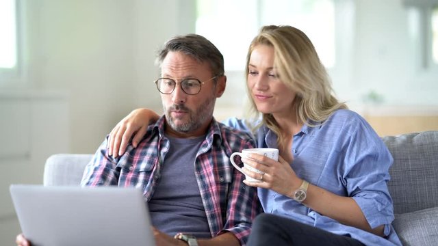 Mature couple connected on internet with laptop - Powered by Adobe