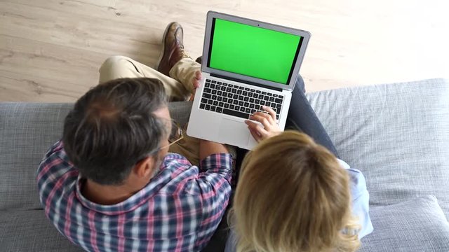 Upper view of couple in sofa using laptop computer