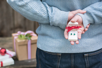Man with secret surprise holiday christmas gift for a woman with a red bow