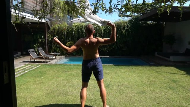 Man standing in his garden and waving with a shirt, slow motion shot at 240fps, steadycam shot 
