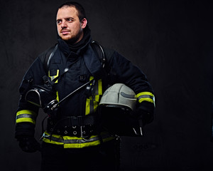 Fototapeta premium Firefighter dressed in uniform holds safety helmet.