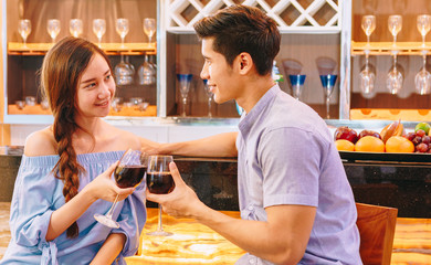 Teen Asian couple drinking wine in front of the bar to drink in their home to celebrate Valentine's day.