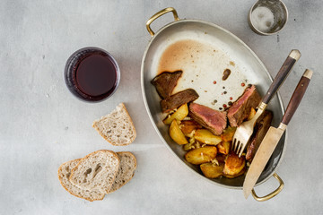Beef steak with potatoes in pan with red wine