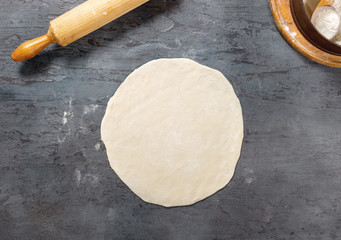 Raw pizza dough on dark surface in bakery, top view