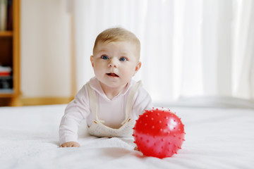 Cute baby playing with red gum ball, crawling, grabbing