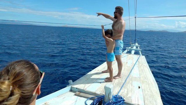 Father standing with his son on the boat and pointing on something, slow motion shot at 240fps, steadycam shot
