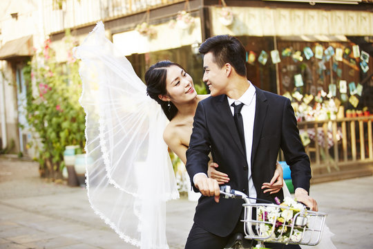 romantic asian newly-wed riding a bicycle