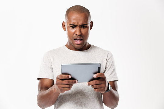 Shocked african man using tablet computer