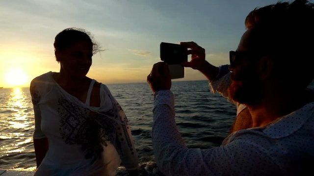 Man doing photos of his girlfriend while sunsetting, slow motion shot at 240fps, steadycam shot    
