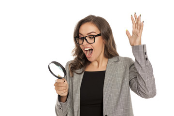 Beautiful young happy woman looking trough the magnifying glass