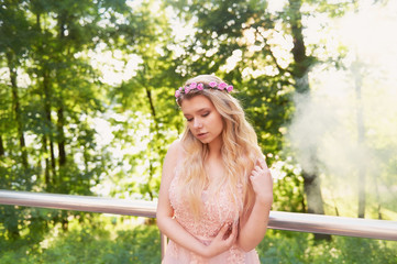 Portrait of a beautiful bride blond girl in pink lace dress ,hair decoration, handmade. Tenderness. The setting sun highlights the clouds of smoke near the face