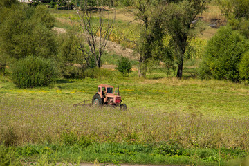 Old red tractor haying in a meadow