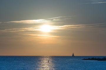 seascape with sailboat and people in boat at sunset