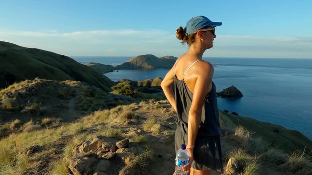 Woman standing on top of the mountain and admires the view, slow motion shot at 240fps, steadycam shot   
