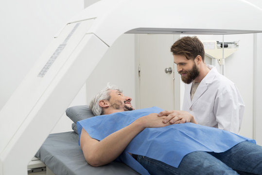 Medical Professional Preparing Man For X-ray Scan In Hospital
