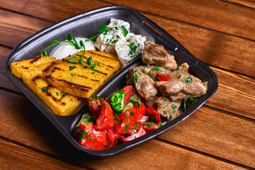 Hominy with meat stew pork, beef and salad in plastic dishes. Street food. Free space for text.