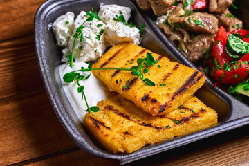 Hominy with meat stew pork, beef and salad in plastic dishes. Street food. Free space for text.
