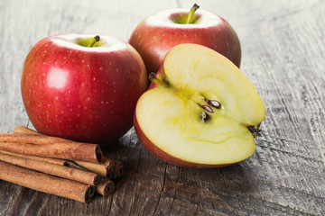 Apples with cinnamon on wooden surface