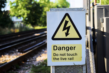 The triangular yellow sign of the danger of electric shock at a local rail station, UK