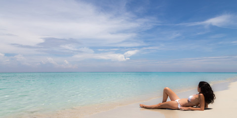 Fototapeta na wymiar Beautiful woman relaxing on a tropical beach. Horizontal banner size, copy space photo