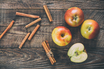Apples with cinnamon on wooden surface