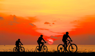 Silhouette man and bike relaxing on blurry sunrise background