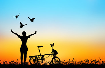 Fototapeta na wymiar silhouette of bird flying out of lady and bicycle .blur background.peace concept.