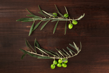 Two olive branches forming frame on dark rustic texture