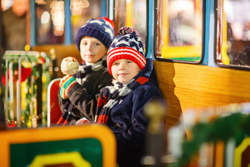 Obraz premium Two little kids boys on carousel at Christmas market