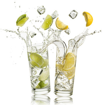 Glass Full Of Water With Lemon And Citron Slices And Ice Cubes Falling And Splashing Water, On White Background