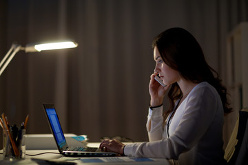 woman with laptop calling on smartphone at office