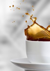 White cup with coffee splashing against blurry grey stairs