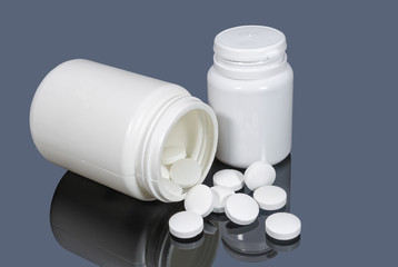 Medical plastic vials with white pills on dark background