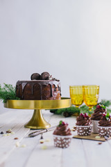 Dark chocolate cake with cookies and cupcakes berries on white wooden background