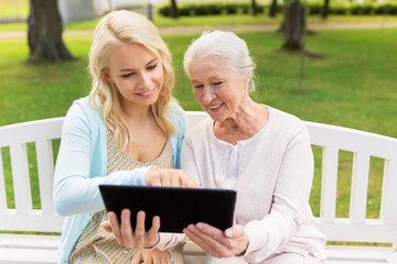 daughter with tablet pc and senior mother at park