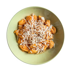 pumpkin gnocchi on white background, top view on green olive plate 