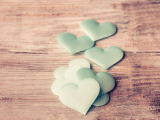 Green pastel hearts on textured wooden table. Valentine's day or baby birthday greeting card. toned