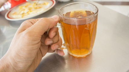 hand holding a cup of hot tea at restaurant