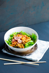 Shrimp tempura spicy salad with fresh lettuce leaves, tomatoes in cream sauce on wooden tray and chopsticks, asian japanese chinese healthy cuisine cultures