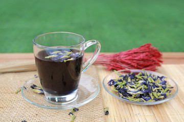 Juice of Butterfly pea in glass on wooden table. Herb drink with Dried Butterfly pea.
