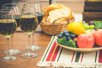 Dinner meal fruit, bread, red and white wine one table, vintage color tone.