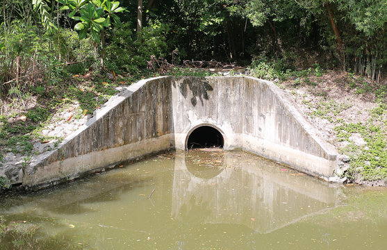 The concrete circular run-off pipe discharging water.