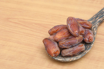 Dates palm fruits in wooden ladle on wooden background