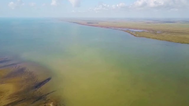 Sacalin Island in the Danube Delta, Romania, separating the Black Sea from the surrounding wetland region with lakes , swamps and low water wildlife habitat, aerial panning shot
