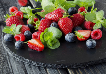 fresh strawberries, raspberries and blueberries on a black background