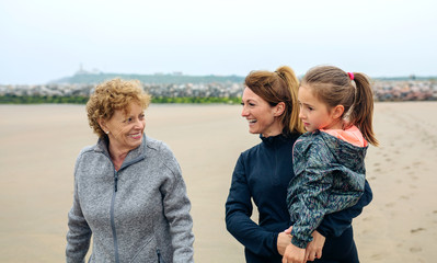 Three generations female walking on the beach in autumn